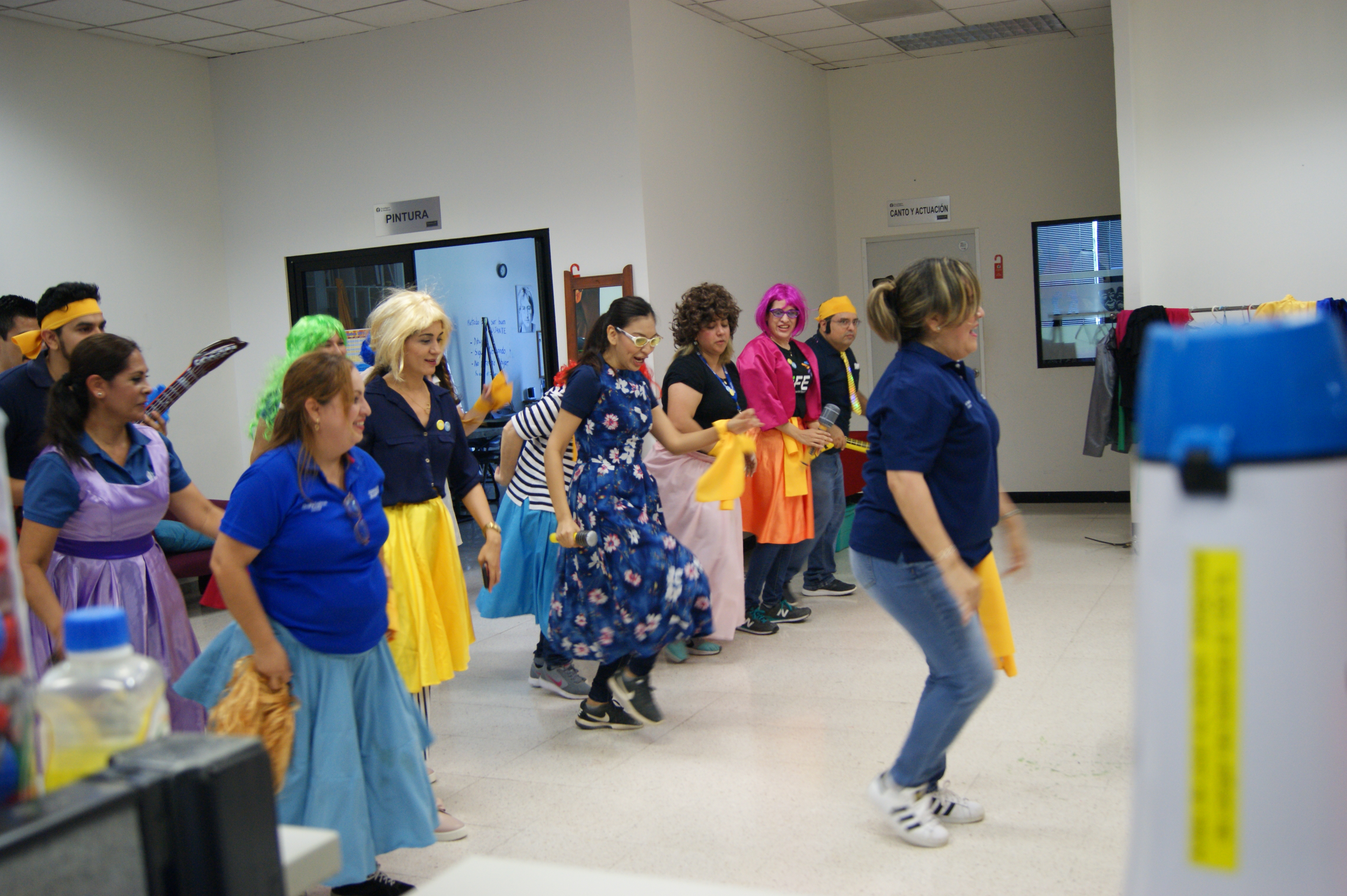 Colaboradores bailando con pelucas y faldas de colores