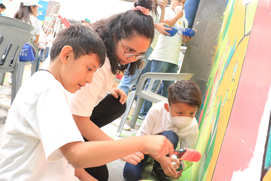 niños y egresados pintando el mural