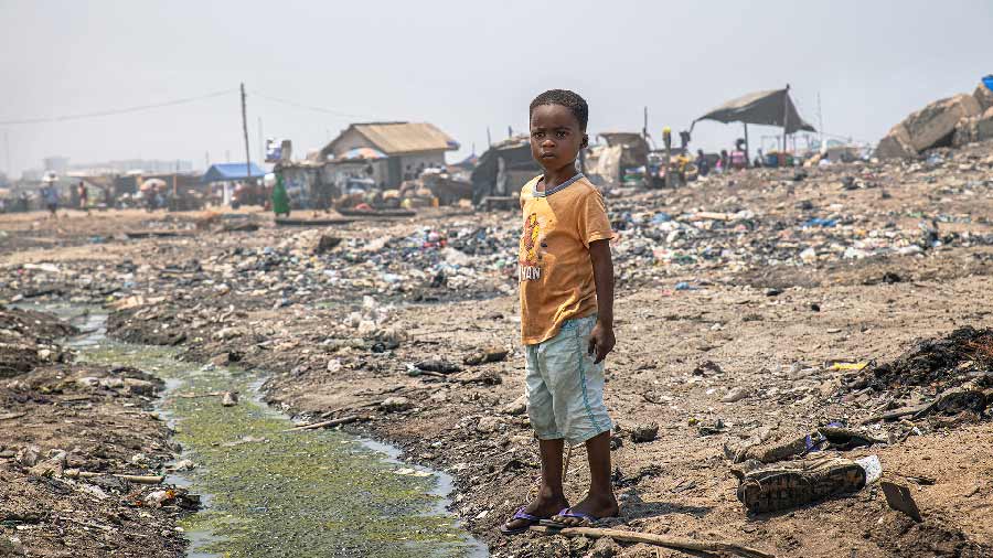 Niño de pie en basurero de Ghana en Africa