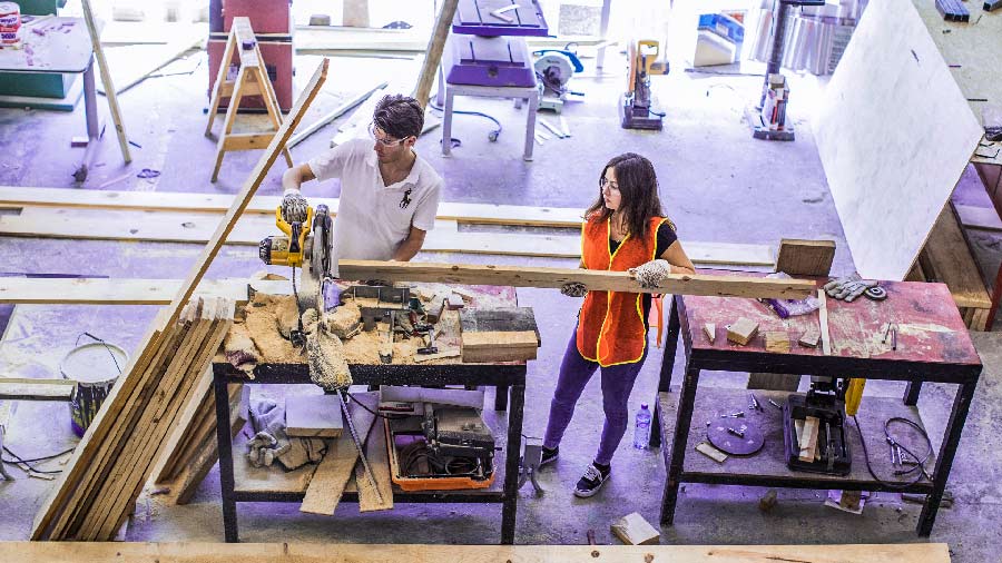 Dos jóvenes manipulando madera en un taller