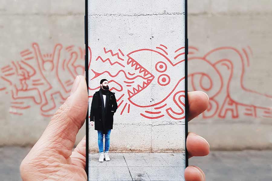 Chico posando en muro mientras amigo captura con realidad aumentada en su celular