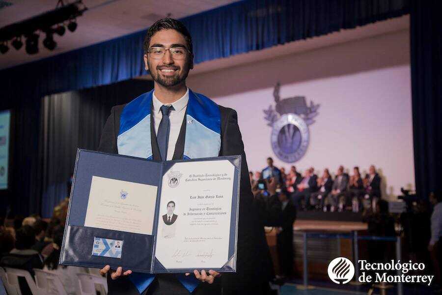Luis Iván mostrando su título universitario en su ceremonia de graduación.