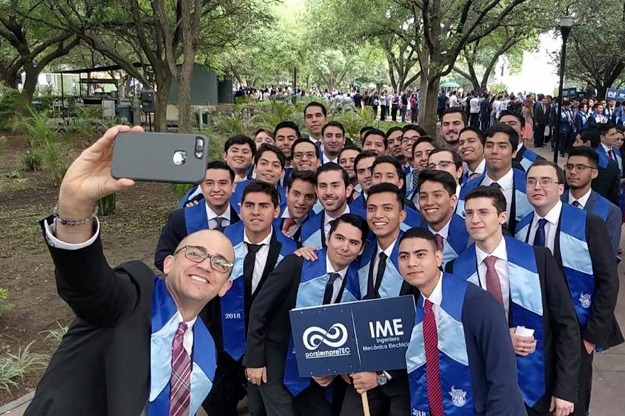Eduardo tomando selfie con alumnos graduados