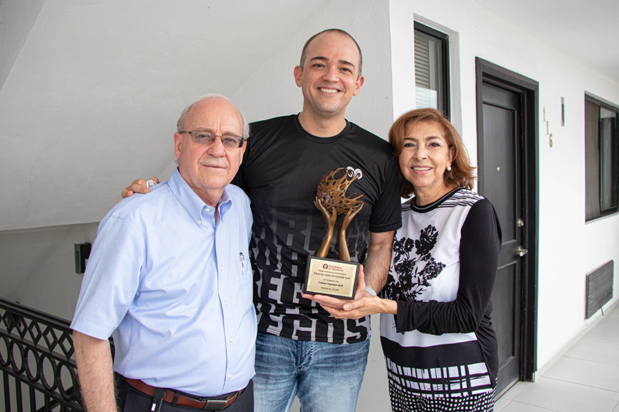Eduardo y sus padres sosteniendo el premio