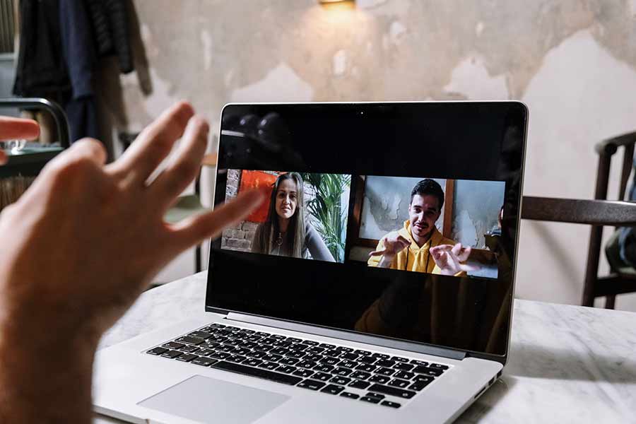 Una persona comunicándose a través de lengua de señas con dos personas a través de una video llamada.