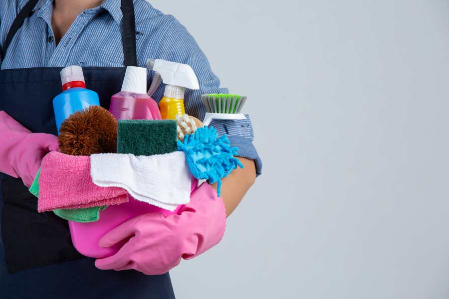 Trabajadora del hogar sosteniendo artículos de limpieza.