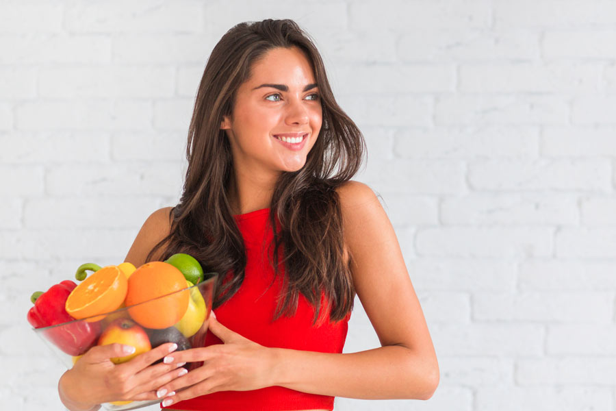 mujer-joven-cargando-un-recipiente-con-frutas-y-verduras