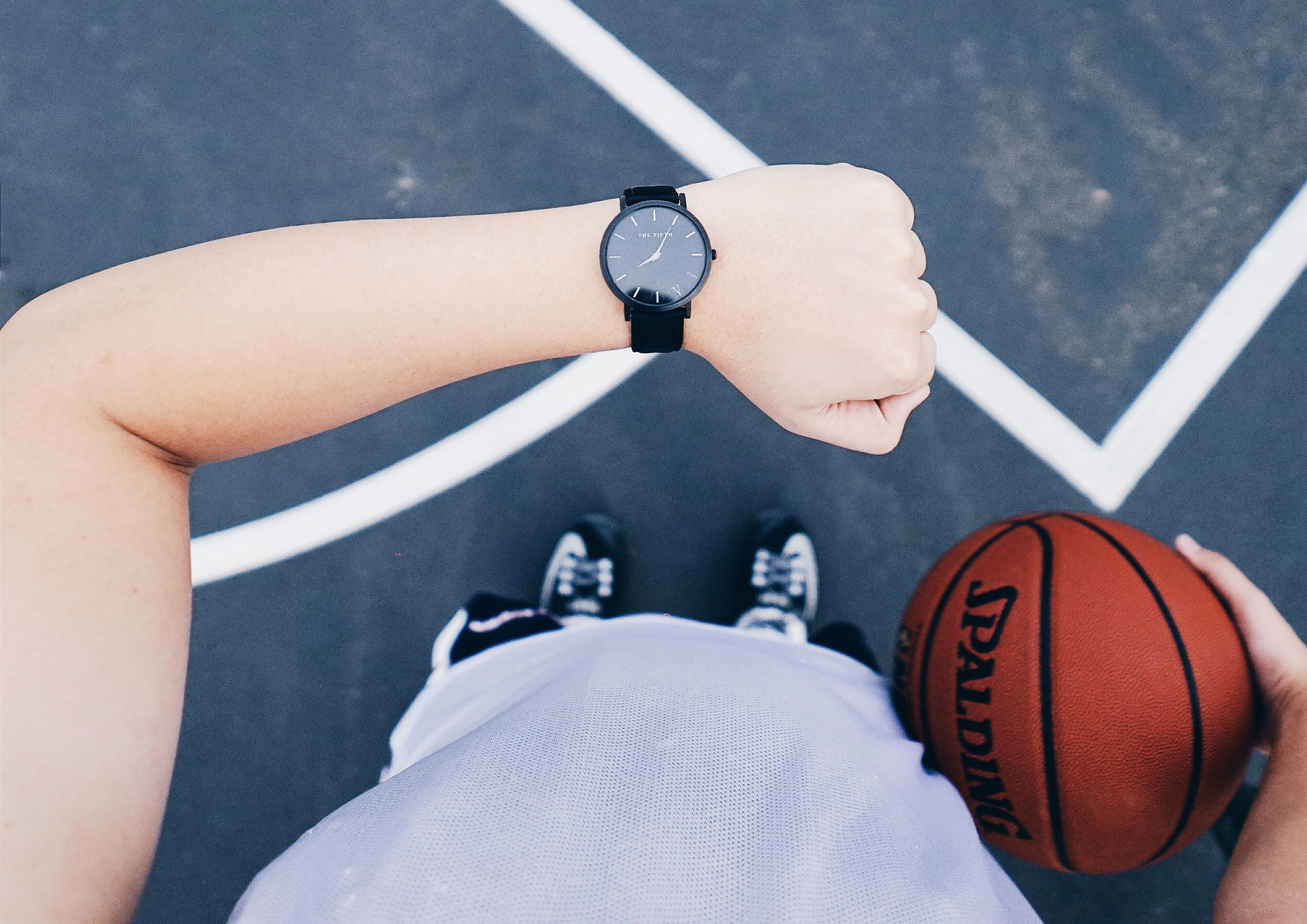 Persona viendo su reloj mientras sostiene un balón de basquetbol