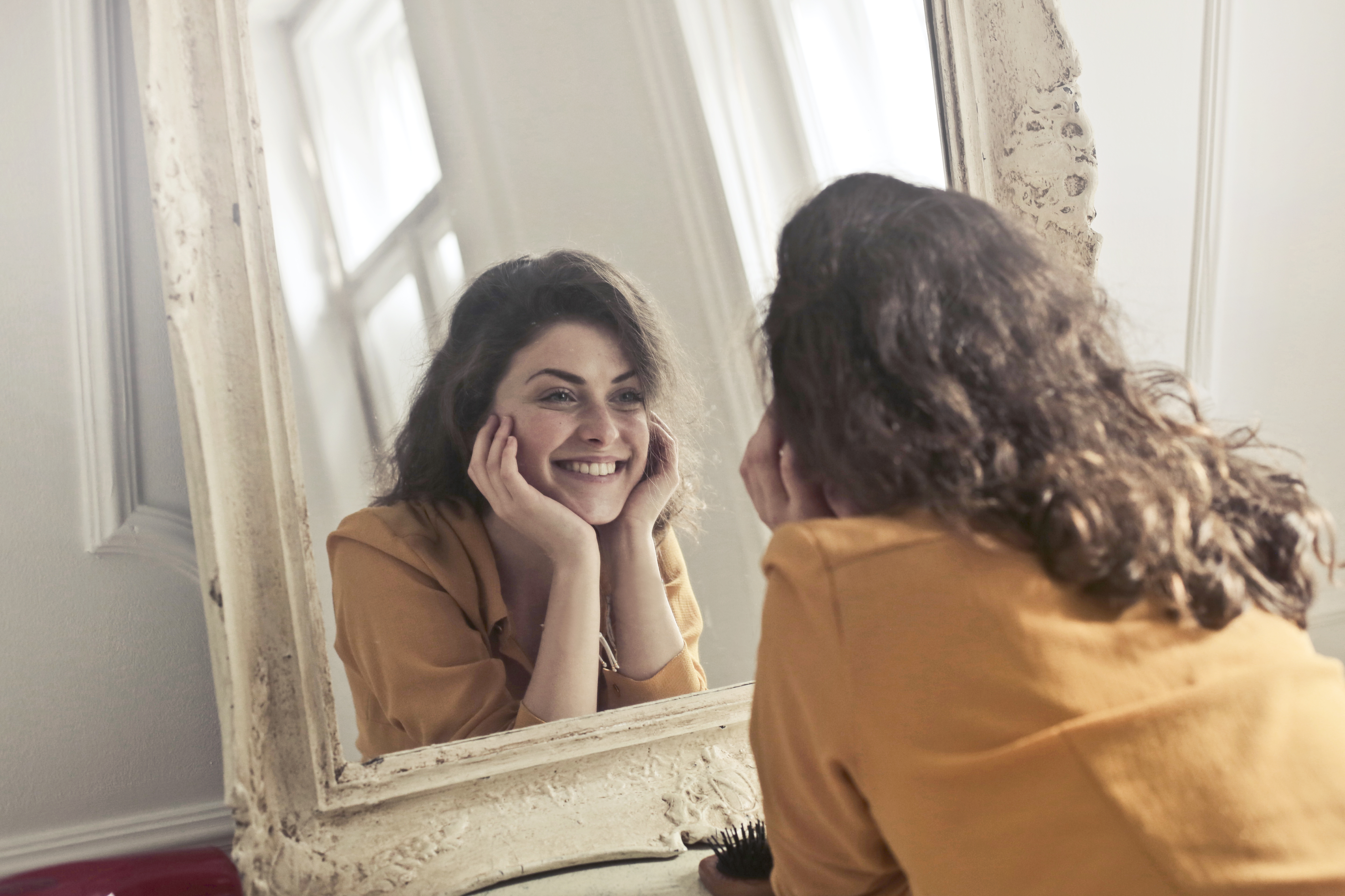 Mujer sonriendo frente al espejo