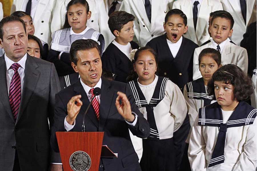 Fotografía del Expresidente Enrique Peña Nieto, atrás de él un grupo de estudiantes haciendo distintos gestos