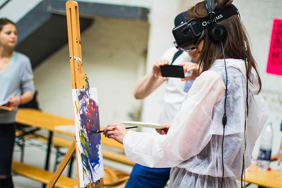 Chica pintando en caballete mientras usa lentes de realidad virtual