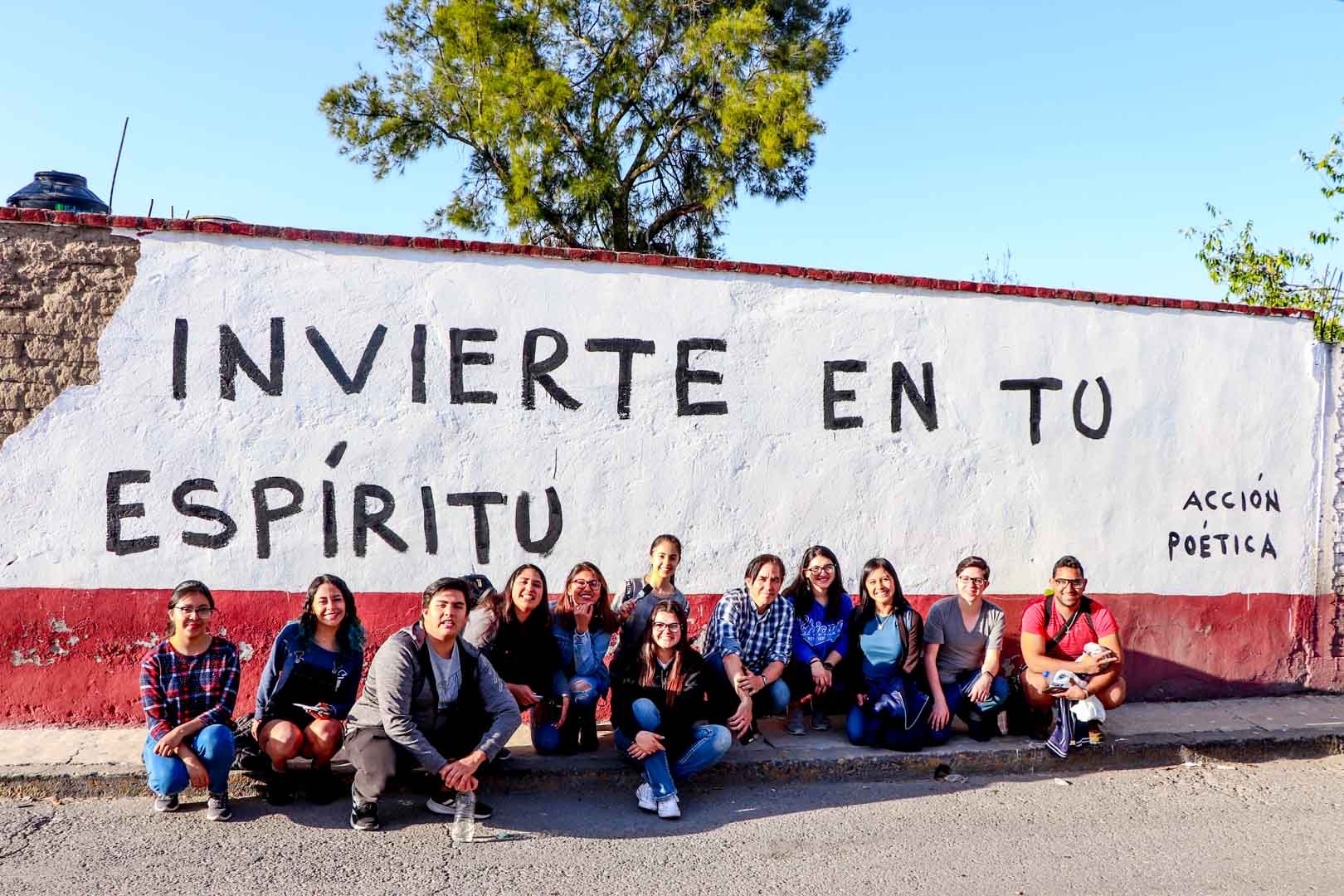 Alumnos y Armando Alanís pintando paredes con frases poéticas