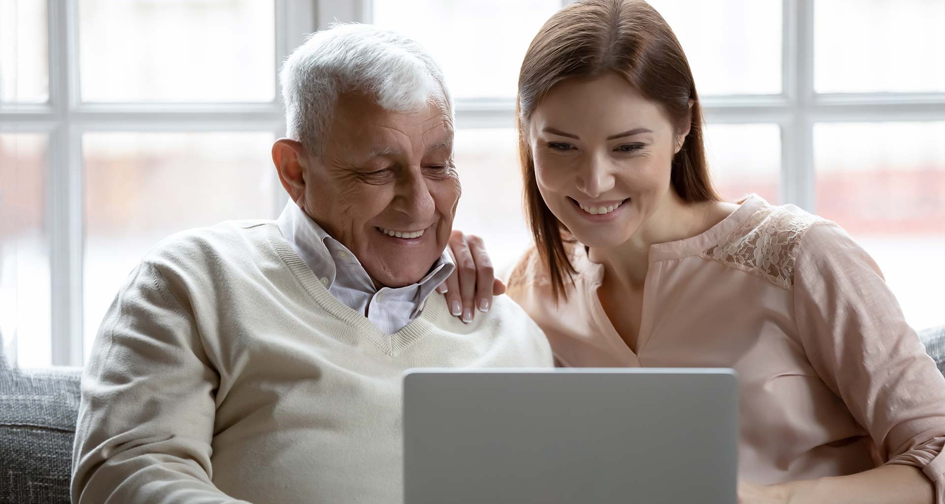 Adulto mayor y mujer joven usando una laptop