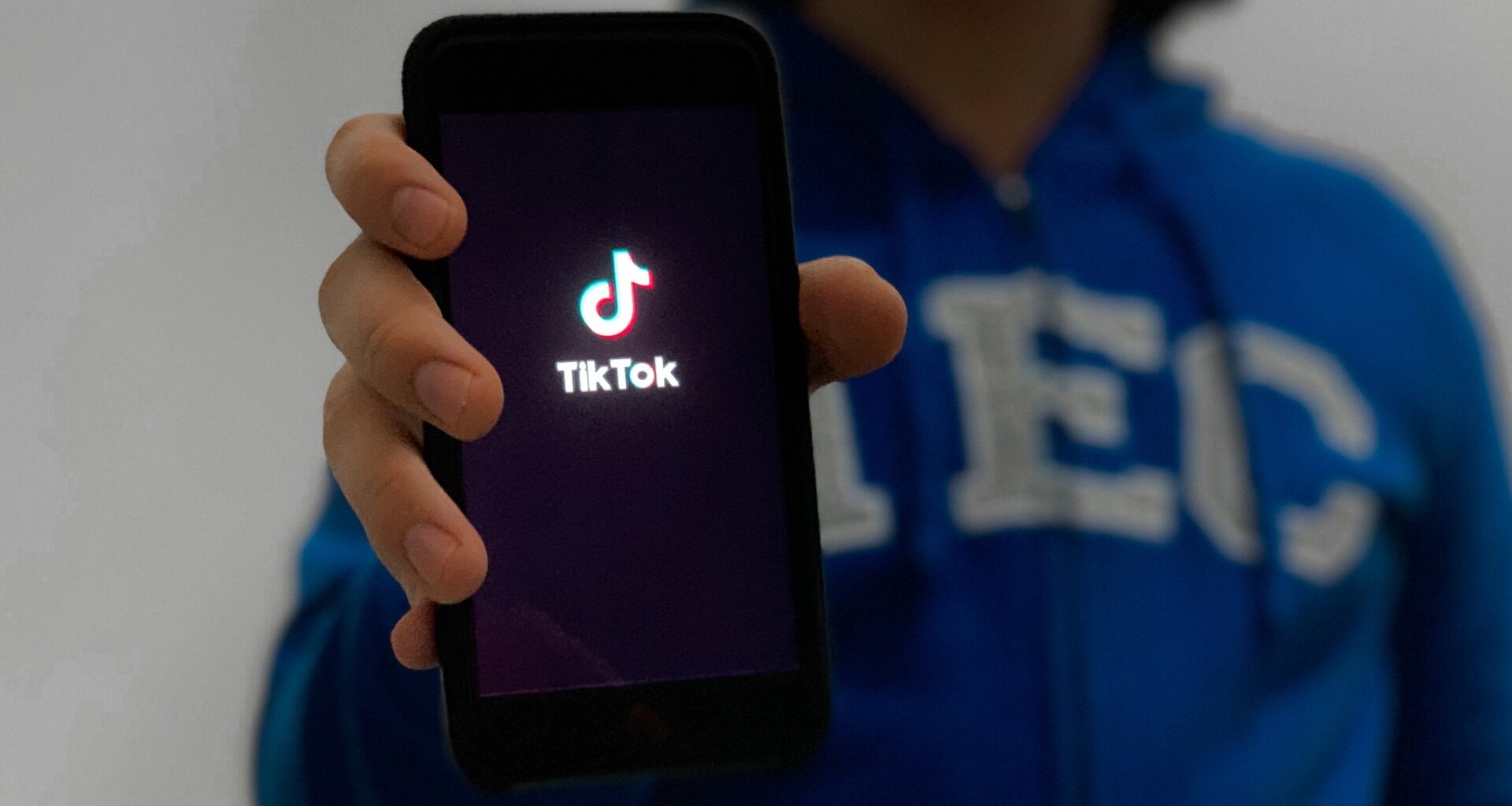 Persona enseñando su celular con la pantalla de inicio de la aplicación de TikTok.