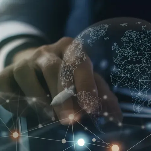 Hand using a digital pen on a screen, with an overlay of a globe connected by nodes and lines, symbolizing global technology and data analysis.