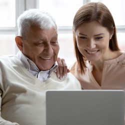 Adulto mayor y mujer joven usando una laptop