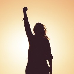Sombra de mujer alzando la mano contra la violencia de género