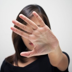 Mujer con palma de la mano abierta, en señal de poner un alto a la violencia de género