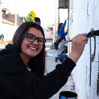 Alumnos y Armando Alanís pintando paredes con frases poéticas